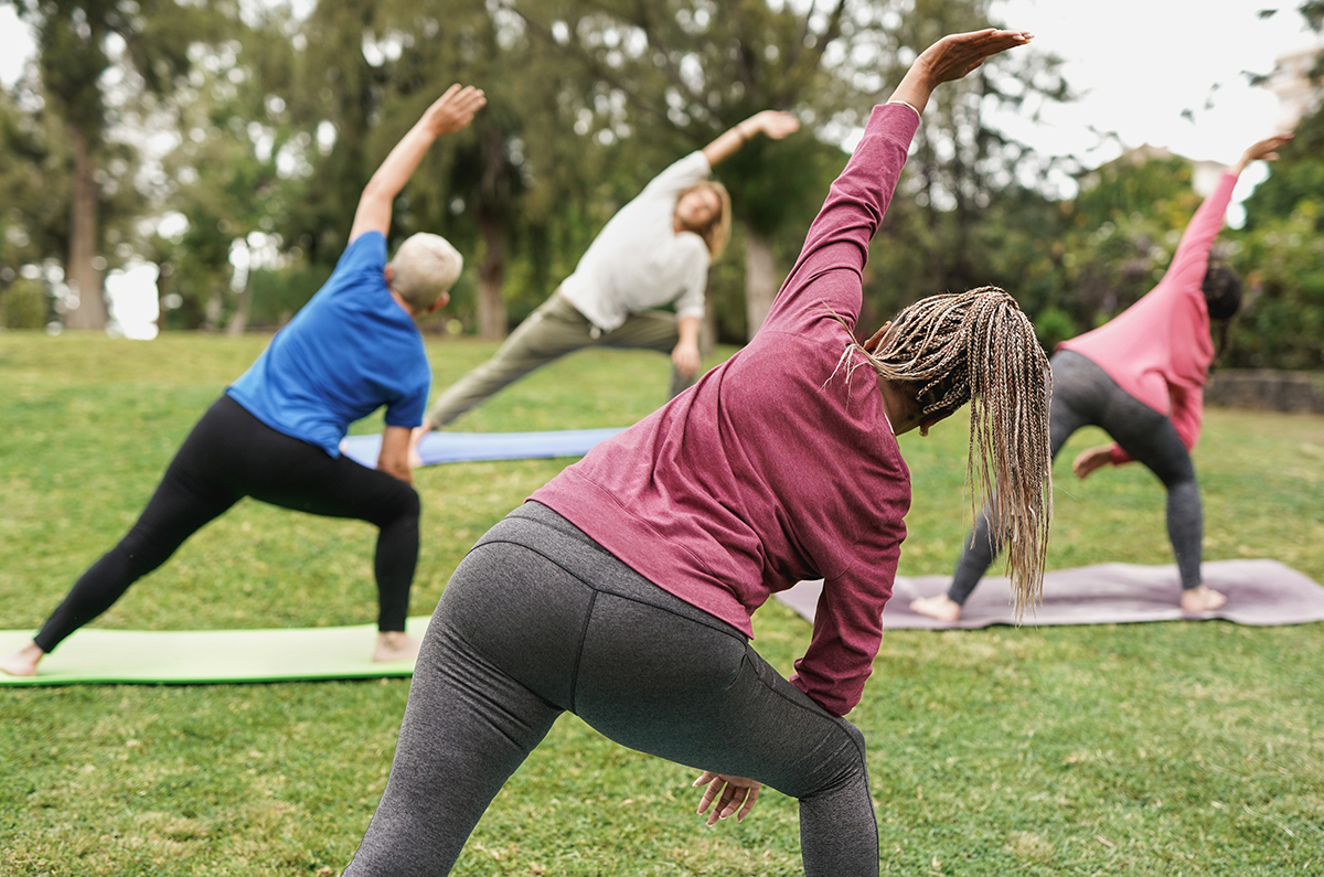 Multiracial people doing yoga at park with social distance for c